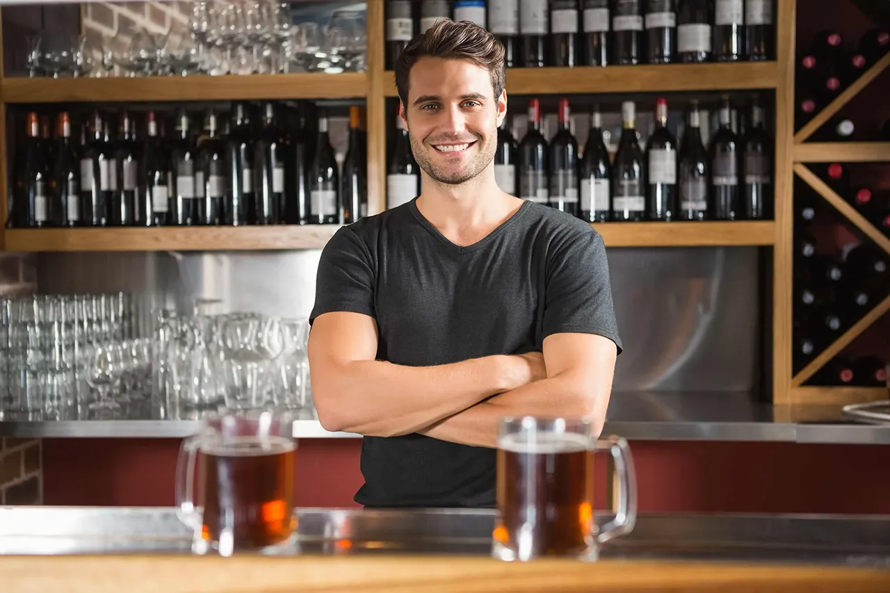 Male bartender standing behind a bar